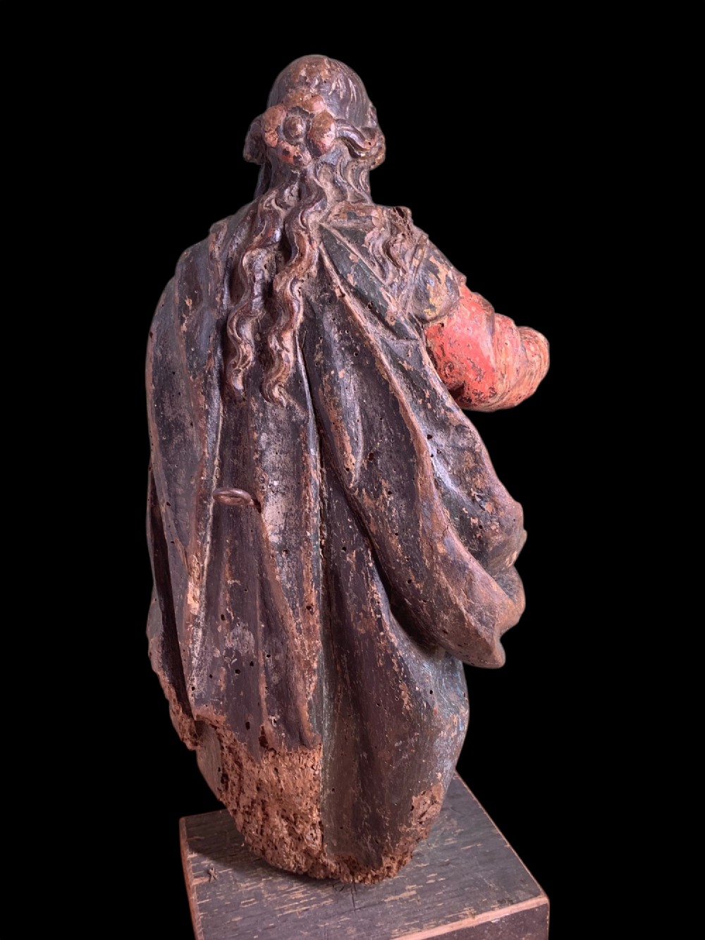 An eighteenth-century carved wood figure of a saint featuring red and blue polychrome paint, set upon a rectangular wooden base. View IX