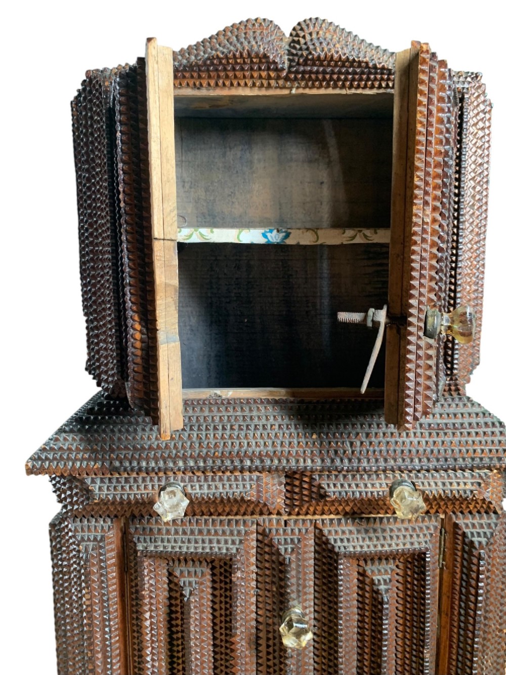 A miniature dark wood tramp art cabinet featuring layered notch-carved geometric borders, double upper doors, and small glass knobs. View VI