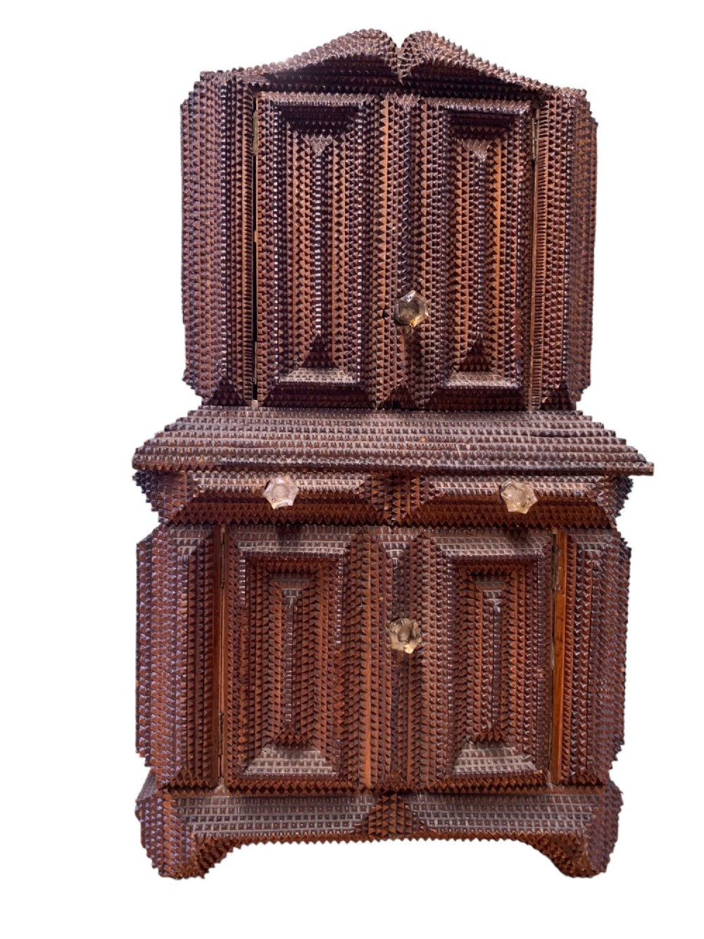 A miniature dark wood tramp art cabinet featuring layered notch-carved geometric borders, double upper doors, and small glass knobs. View X