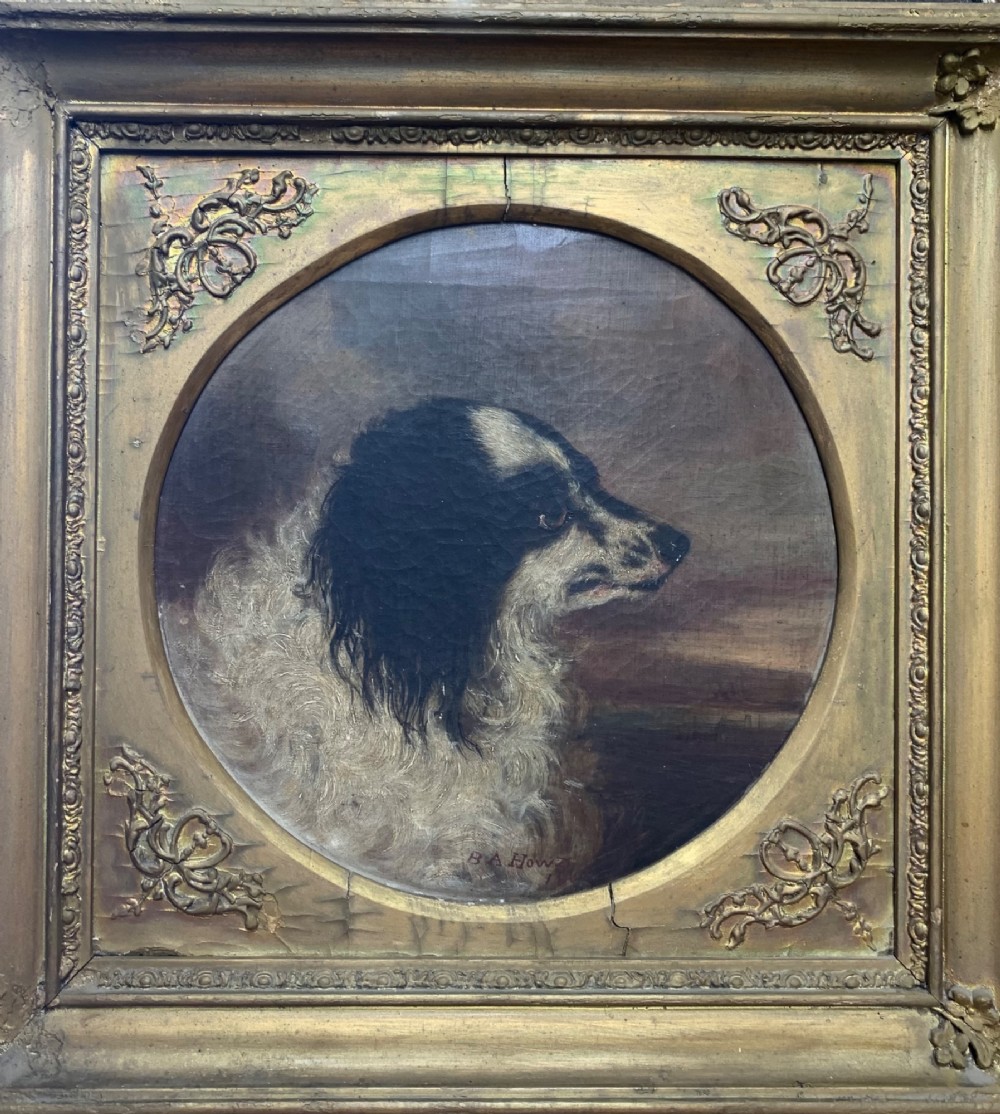 A 19th-century profile portrait painting of a black and white spaniel in oil, set inside a gold giltwood frame with an oval spandrel mount.