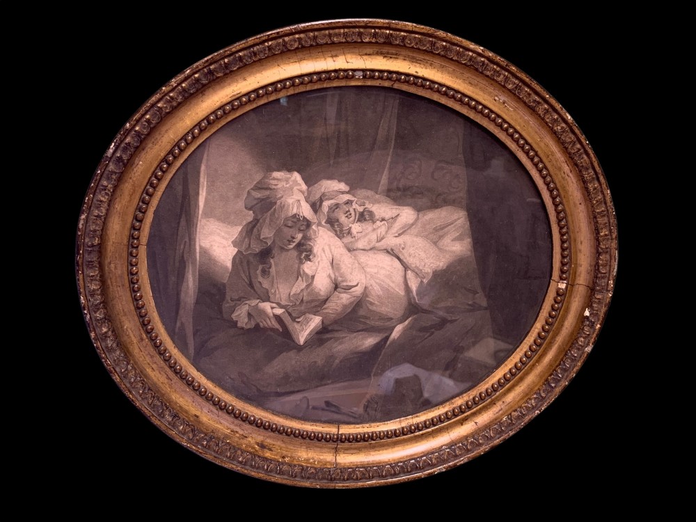 An oval 18th-century sepia print displaying a domestic bedroom scene, enclosed within a carved circular giltwood frame with beaded detailing.