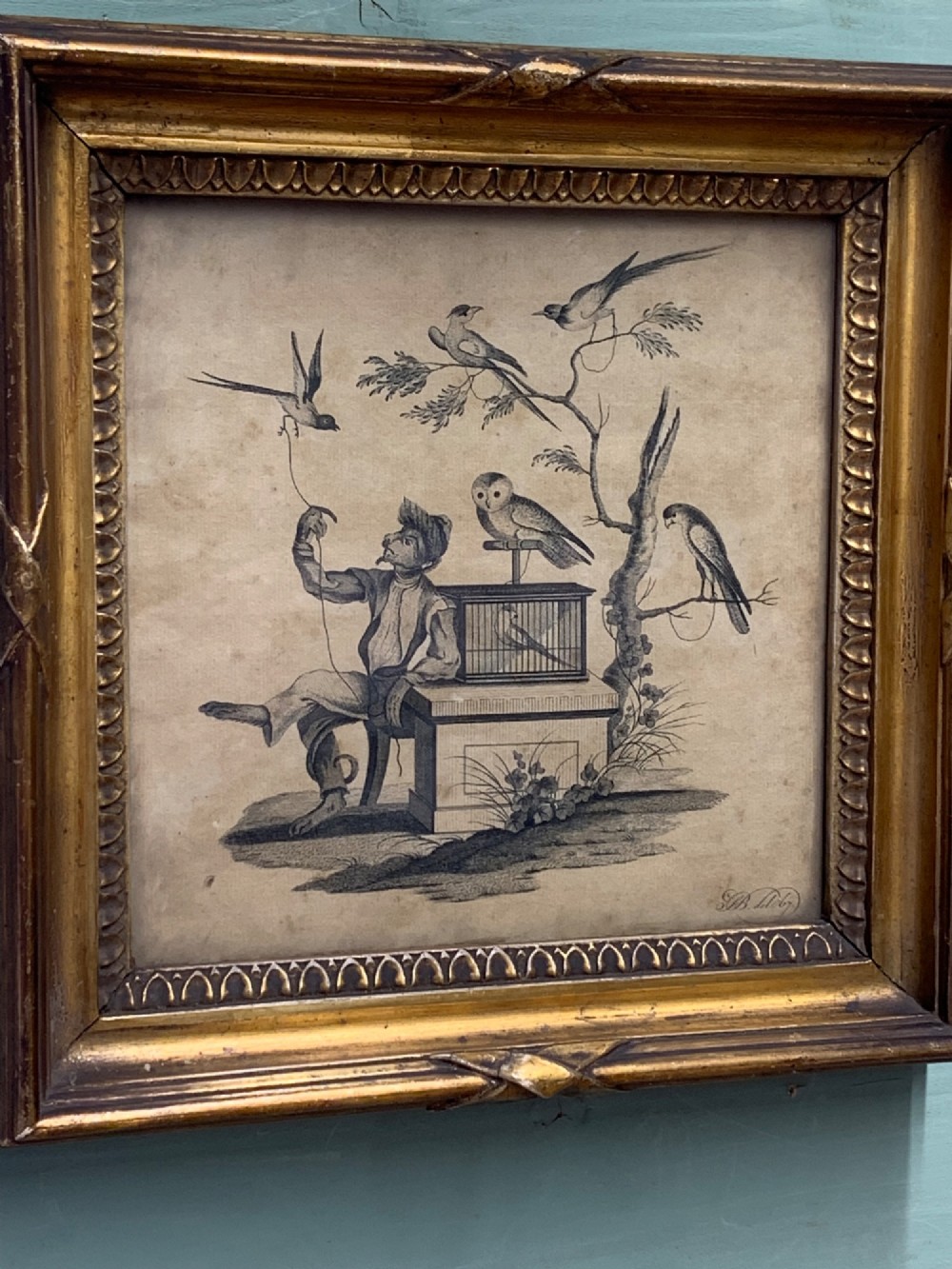 An 18th-century monochrome etching featuring a clothed monkey seated beside a birdcage surrounded by birds, enclosed in an ornate gold leaf frame. View III