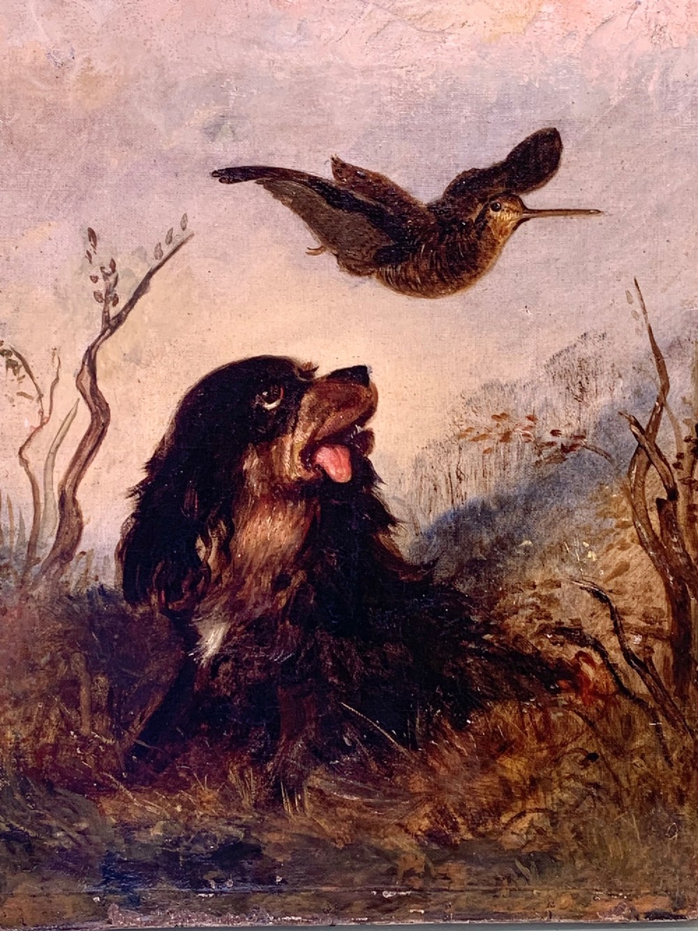 A 19th-century oil painting depicting a black and tan spaniel seated in a landscape looking upward at a woodcock bird in flight. View IV
