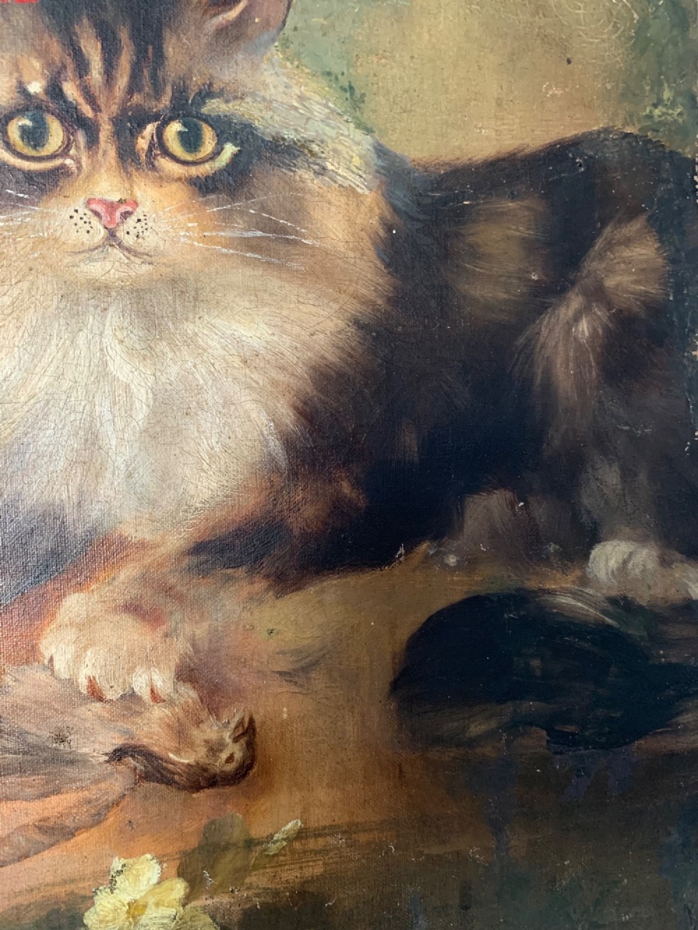 A 19th-century naive school oil painting depicting a fluffy longhaired cat holding a small bird, set beside pale cream flowers against a warm brown background. View V