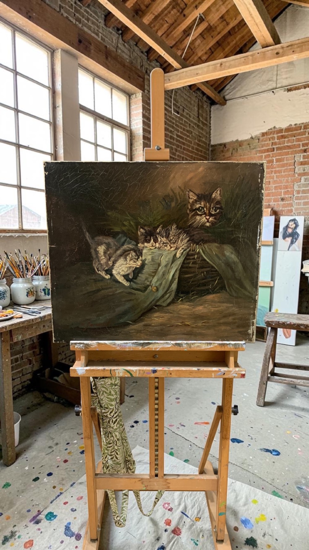 An antique oil painting depicting four kittens and a cat observing a small snail on a green cloth beside a woven basket. View II