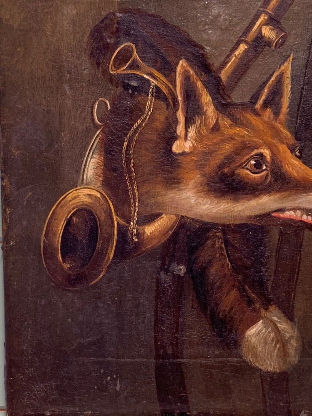 A 19th-century oil painting on canvas depicting a fox head trophy alongside a brass hunting horn and whip against a dark brown background. View V