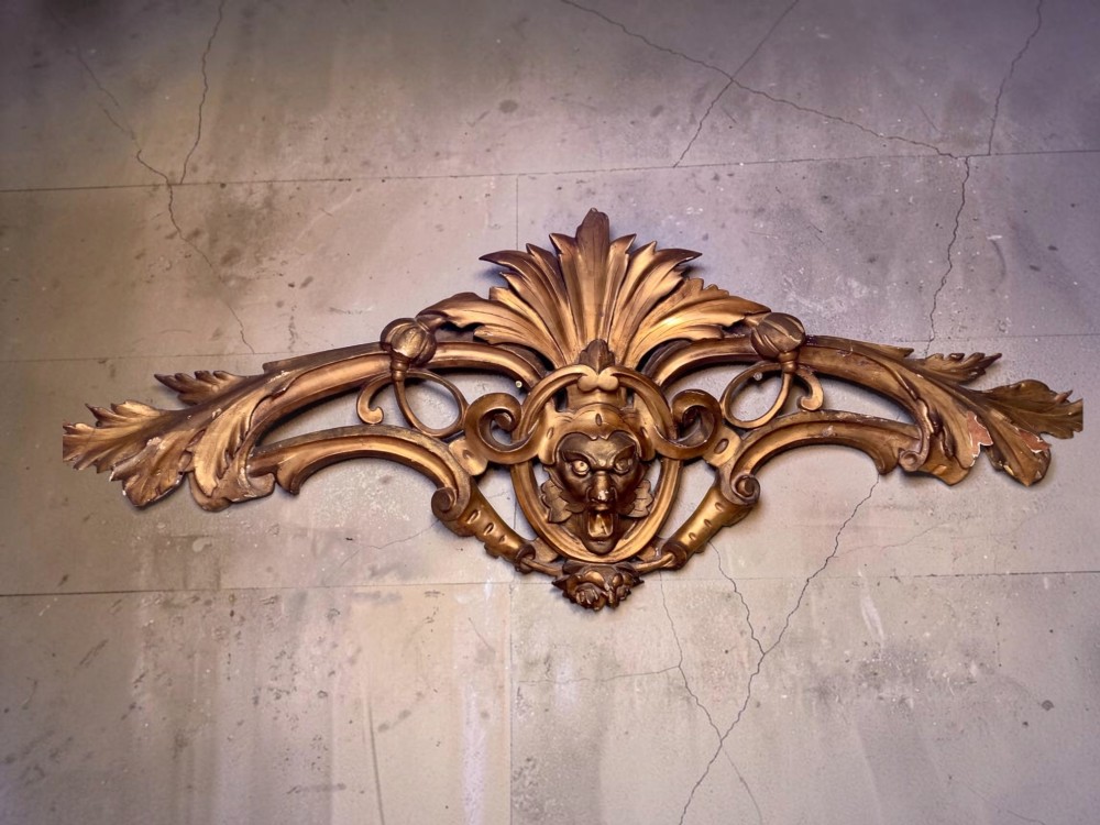 A set of three carved gold giltwood wall fragments decorated with central mascaron faces and scrolling acanthus leaves. View III