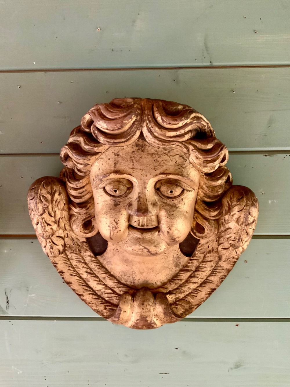 A pair of French carved wooden church angel heads featuring curly hair and sculpted wings framing the face with remnants of gilded paint. View IV