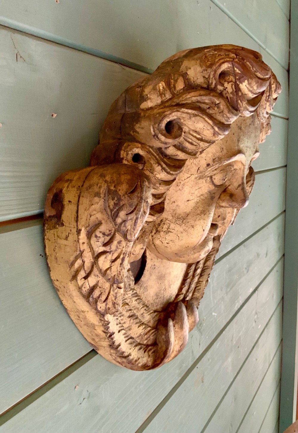 A pair of French carved wooden church angel heads featuring curly hair and sculpted wings framing the face with remnants of gilded paint. View VI