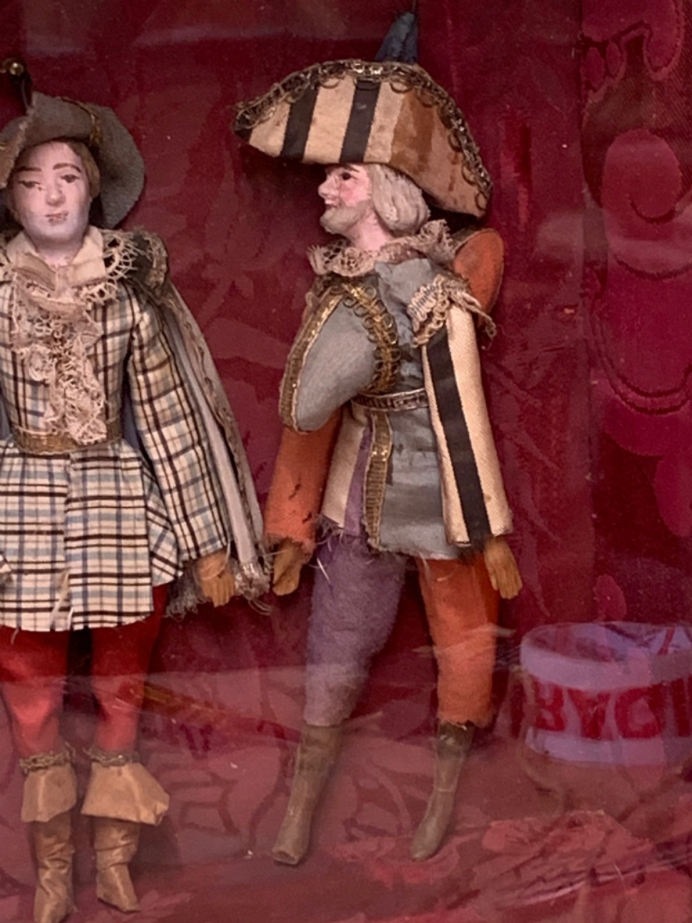 An antique gilt-framed shadow box diorama depicting four miniature costumed theatrical figures against a crimson draped fabric backdrop. View VII