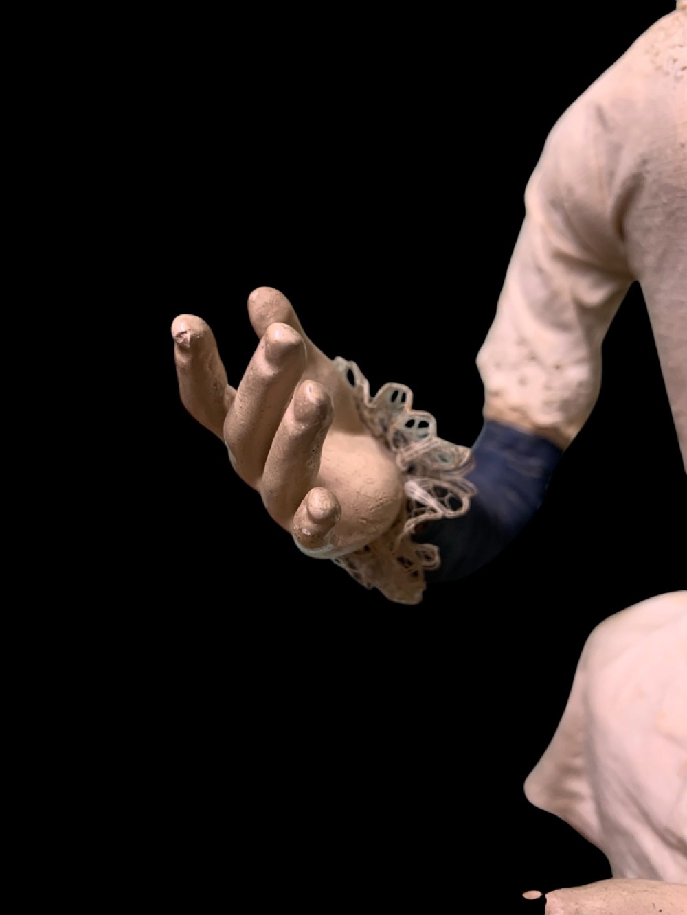 A 19th-century processional mannequin with carved polychrome head and hands, dressed in cream fabric with dark blue sleeves, standing on a four-legged wooden cage base. View VI