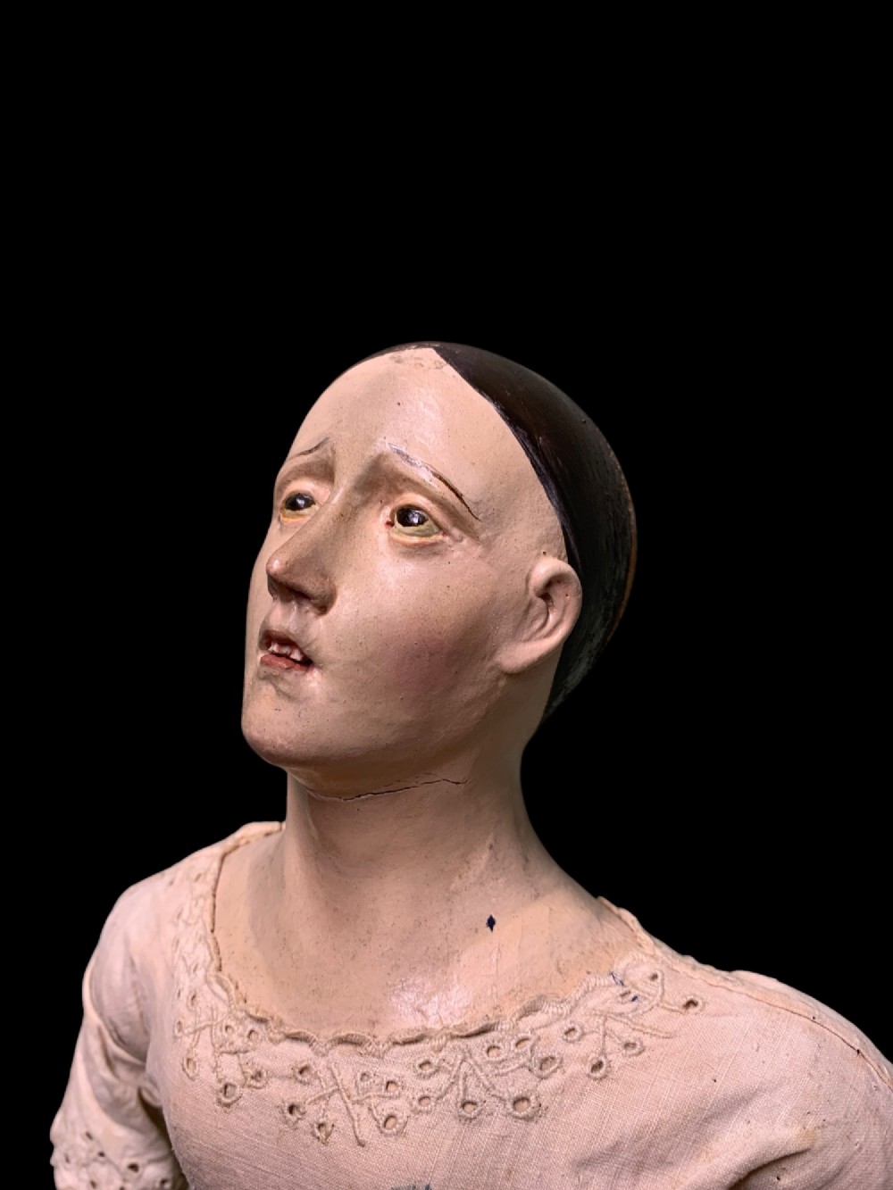 A 19th-century processional mannequin with carved polychrome head and hands, dressed in cream fabric with dark blue sleeves, standing on a four-legged wooden cage base. View VII
