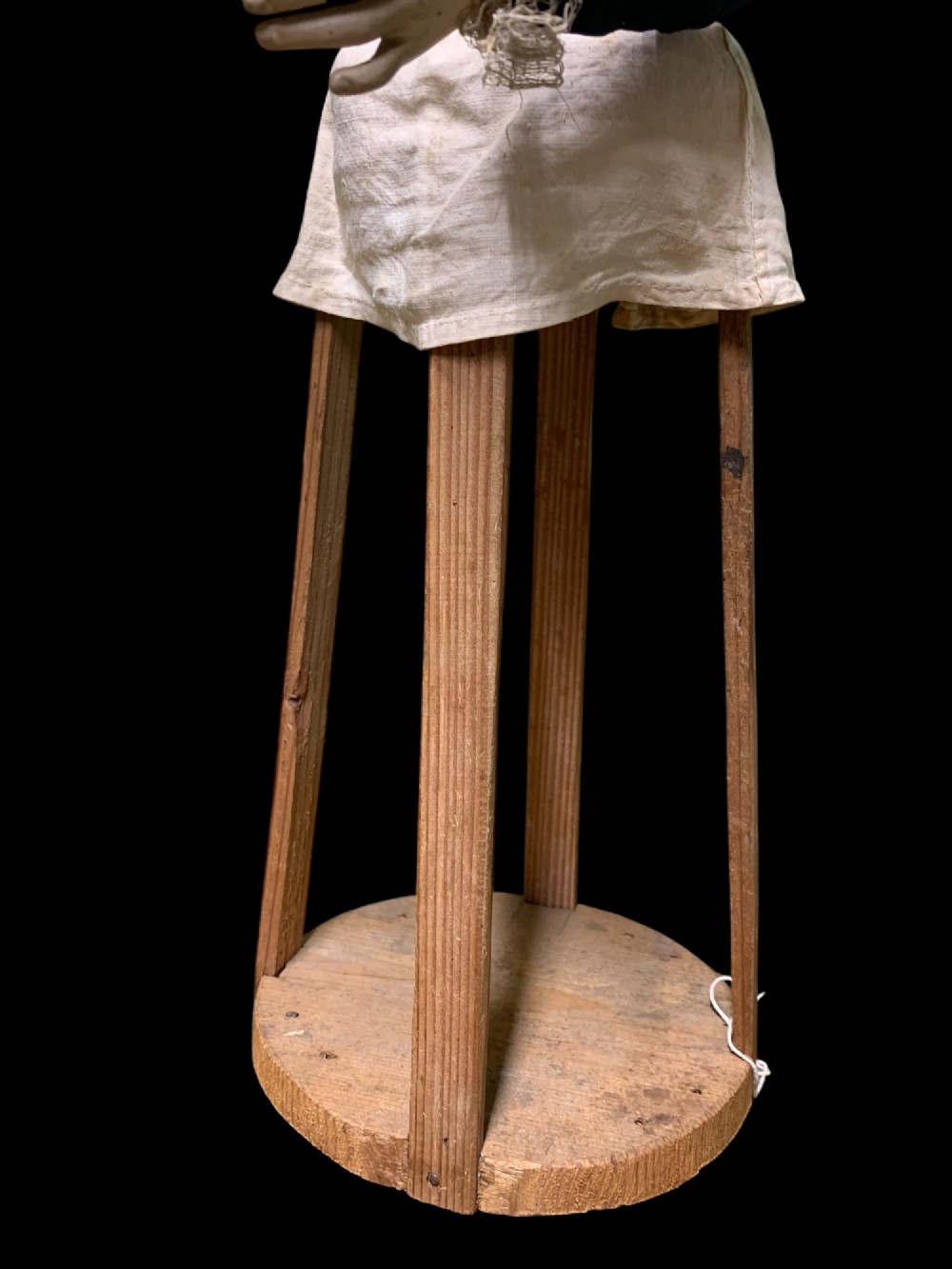A 19th-century processional mannequin with carved polychrome head and hands, dressed in cream fabric with dark blue sleeves, standing on a four-legged wooden cage base. View X