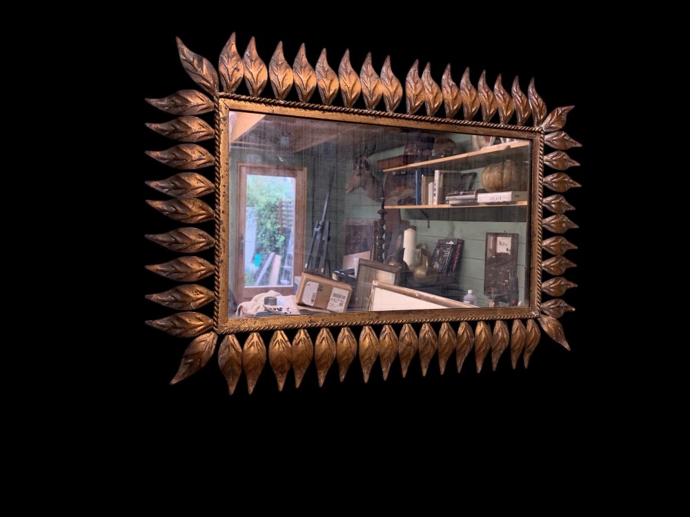 A rectangular horizontal landscape mirror framed in aged gilt metal surrounded by radiating leaf-shaped motifs and a inner rope-twist border. View III