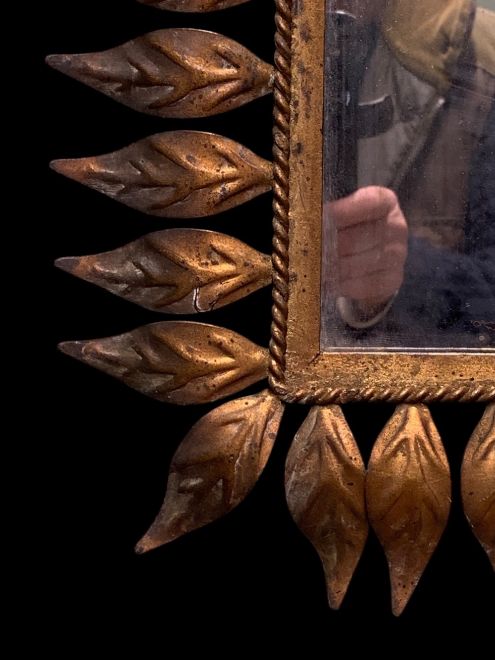 A rectangular horizontal landscape mirror framed in aged gilt metal surrounded by radiating leaf-shaped motifs and a inner rope-twist border. View VII