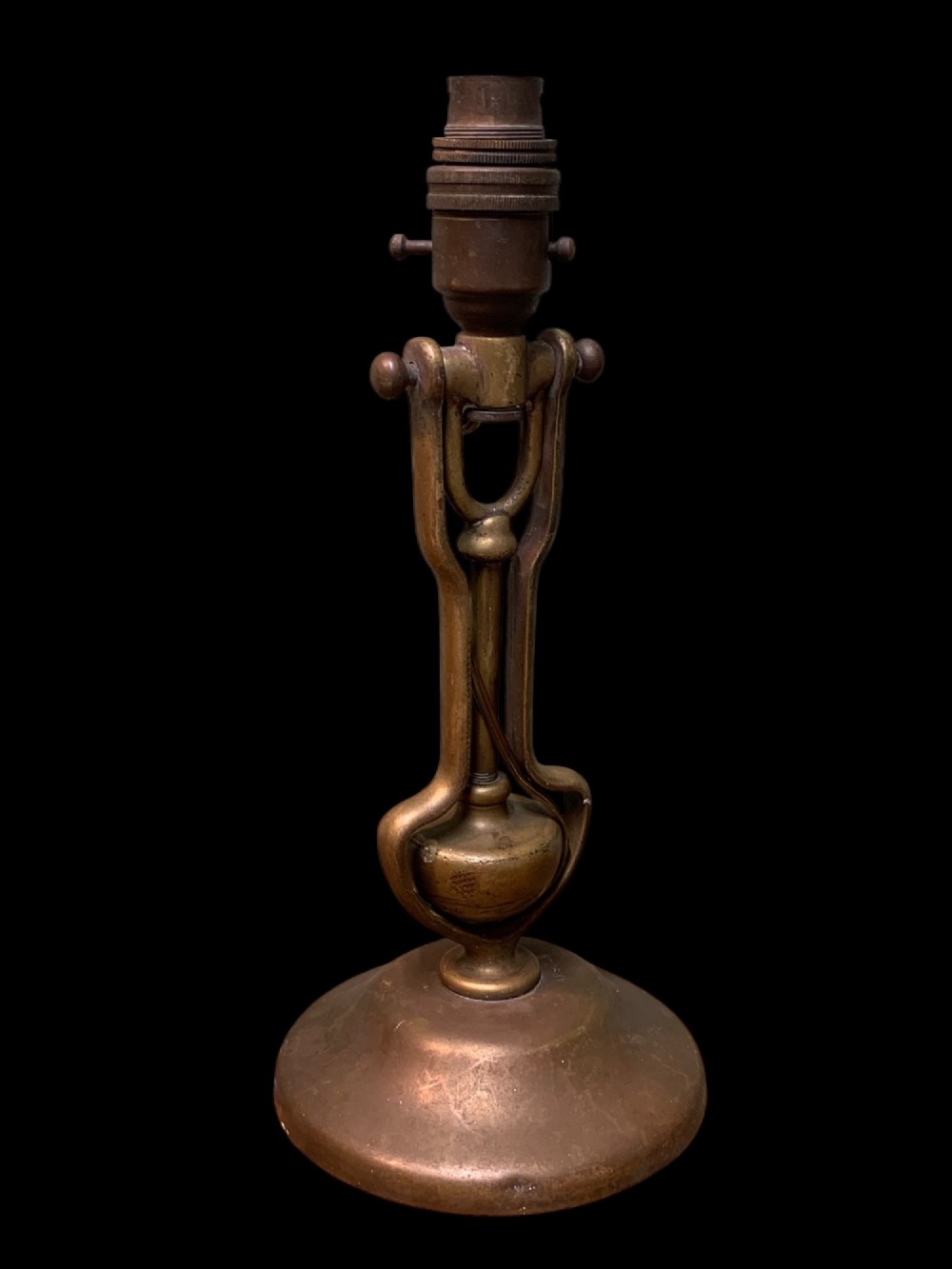 An early twentieth-century patinated brass gimballed ship table lamp featuring a weighted circular base and articulated swivel mechanism.