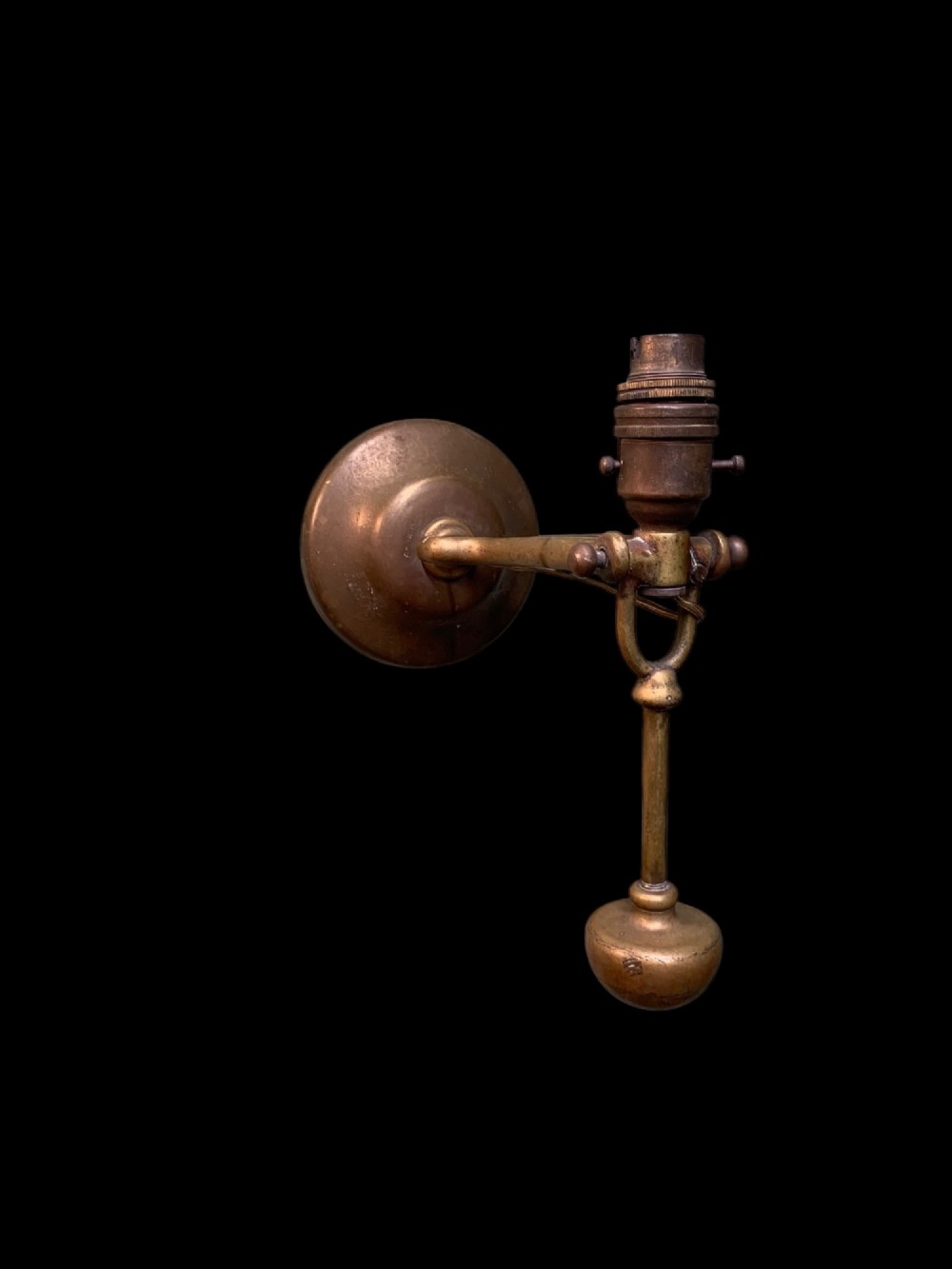 An early twentieth-century patinated brass gimballed ship table lamp featuring a weighted circular base and articulated swivel mechanism. View III