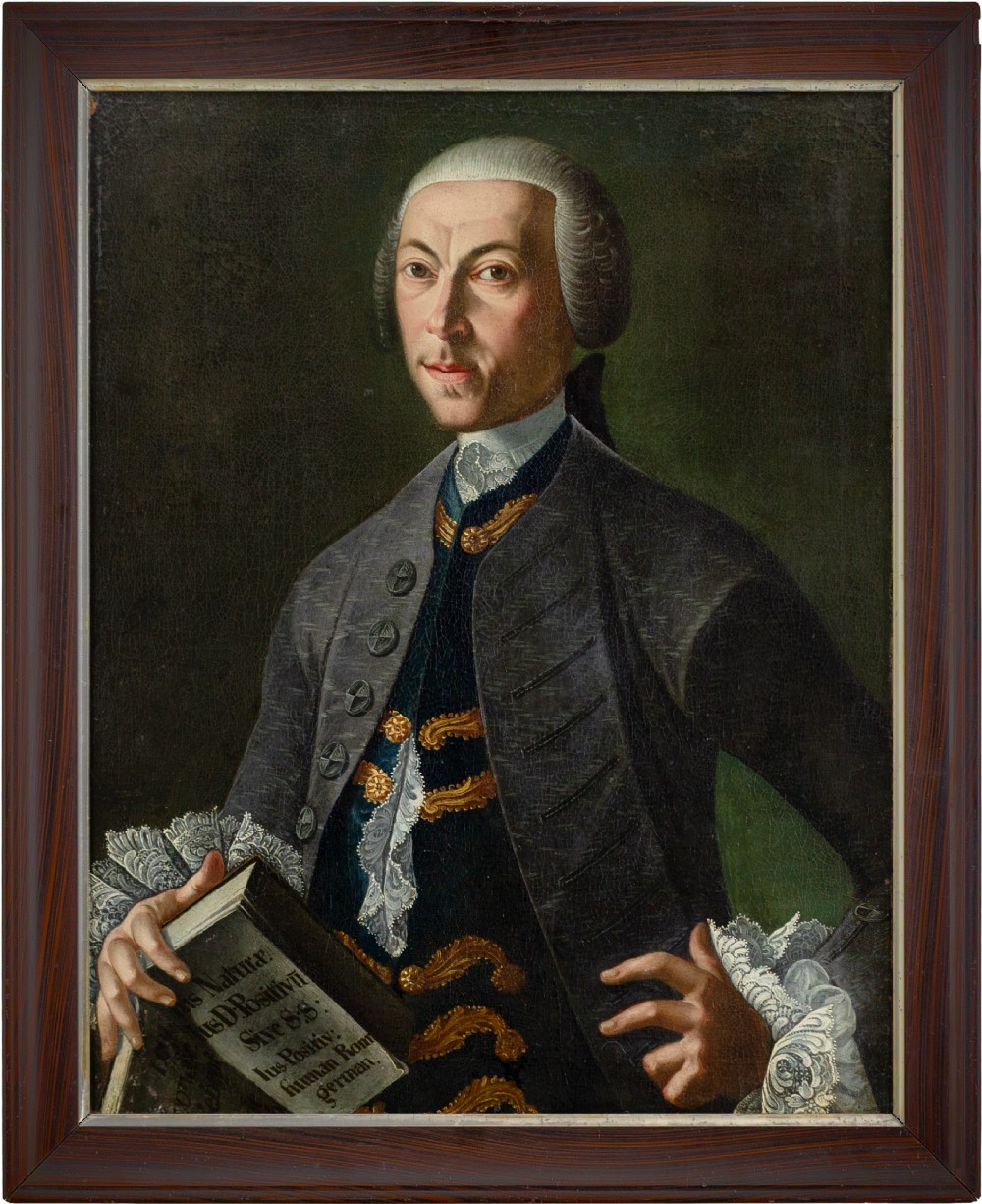 An 18th-century oil portrait of a scholar wearing a wig, grey coat, and lace cuffs, holding a Latin text book set within a dark wooden frame.