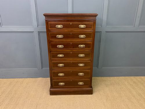 fig 2. A tall Edwardian mahogany pillar chest featuring seven inlaid drawers with brass drop handles on a plinth base.