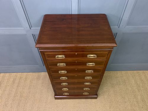 fig 3. A tall Edwardian mahogany pillar chest featuring seven inlaid drawers with brass drop handles on a plinth base.