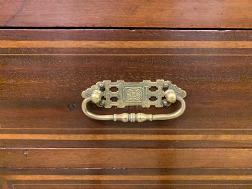 fig 4. A tall Edwardian mahogany pillar chest featuring seven inlaid drawers with brass drop handles on a plinth base.