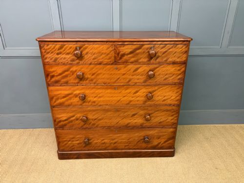 fig 1. A Victorian chest of drawers in warm brown figured timber featuring turned handles and a plinth base.