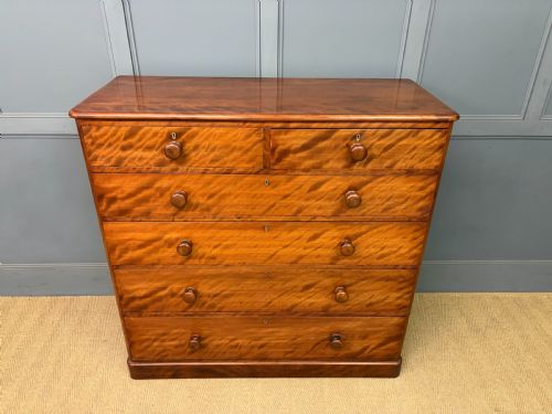 fig 2. A Victorian chest of drawers in warm brown figured timber featuring turned handles and a plinth base.