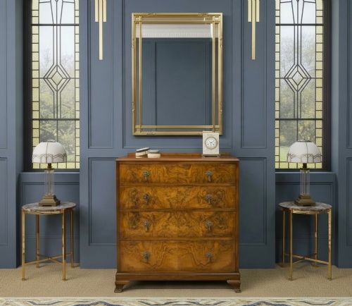 fig 1. An Art Deco burr walnut chest of four full-width drawers featuring figured veneer panels, decorative brass drop handles, and low bracket feet.