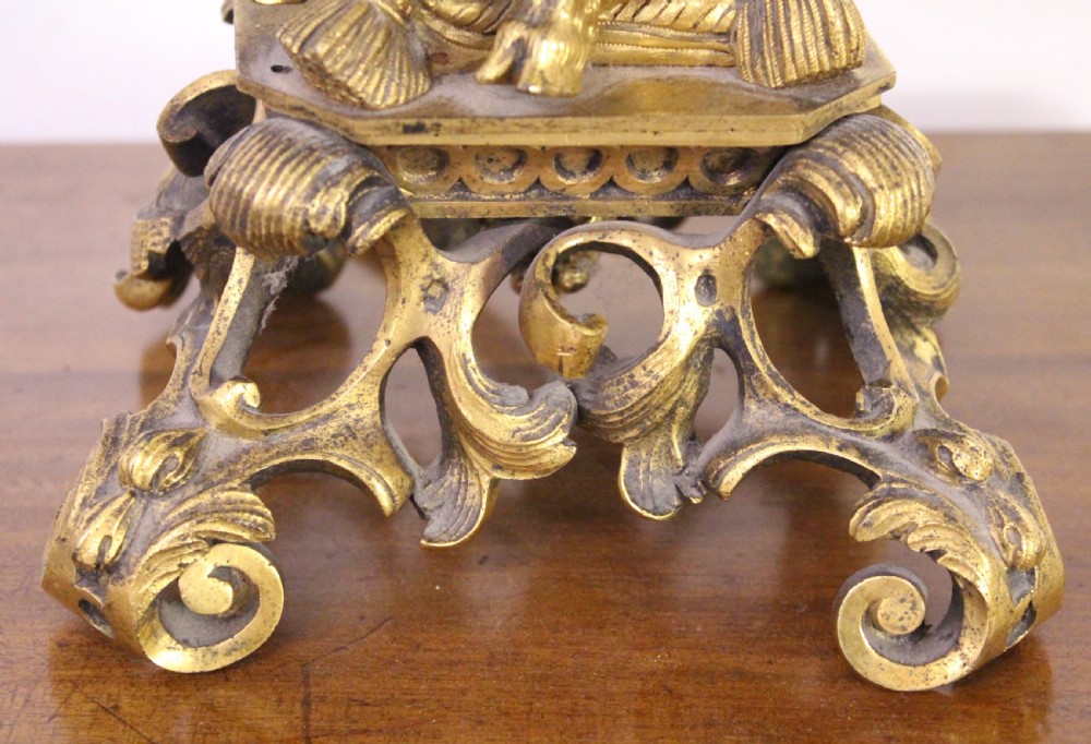 A gilt bronze table lamp featuring a central sculptural cherub figure playing a flute, supporting three scrolling light arms with cream fringed shades. View IV