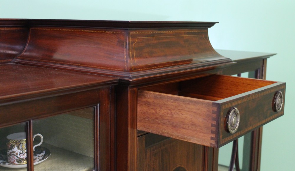 An Edwardian inlaid mahogany side cabinet featuring two outer glazed display doors, a central wooden door with an oval inlay panel, and square tapered legs. View XVIII