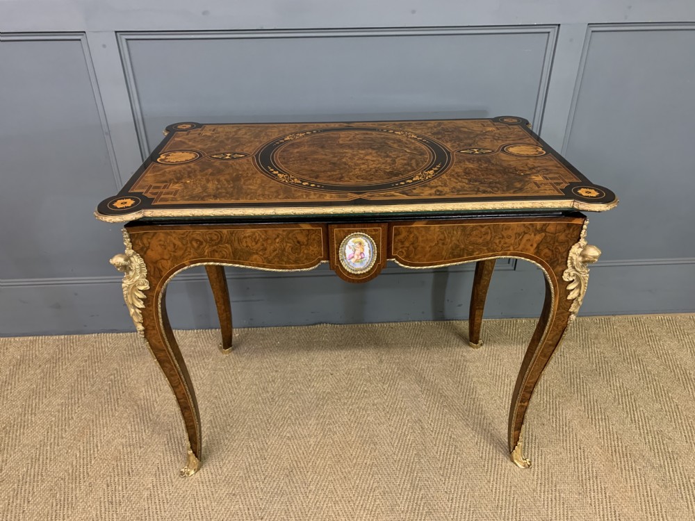 A 19th-century French burr walnut card table featuring intricate marquetry on the top, cabriole legs with gilt-bronze mounts, and a central porcelain plaque on the frieze. View XIII