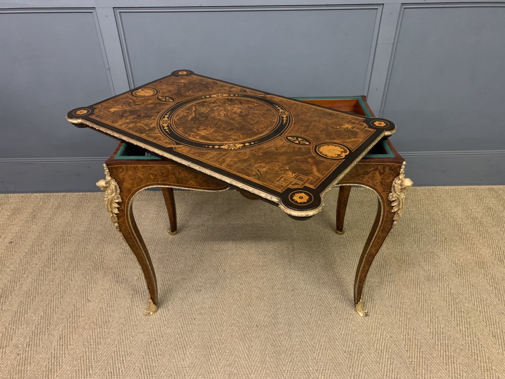 A 19th-century French burr walnut card table featuring intricate marquetry on the top, cabriole legs with gilt-bronze mounts, and a central porcelain plaque on the frieze. View XIX