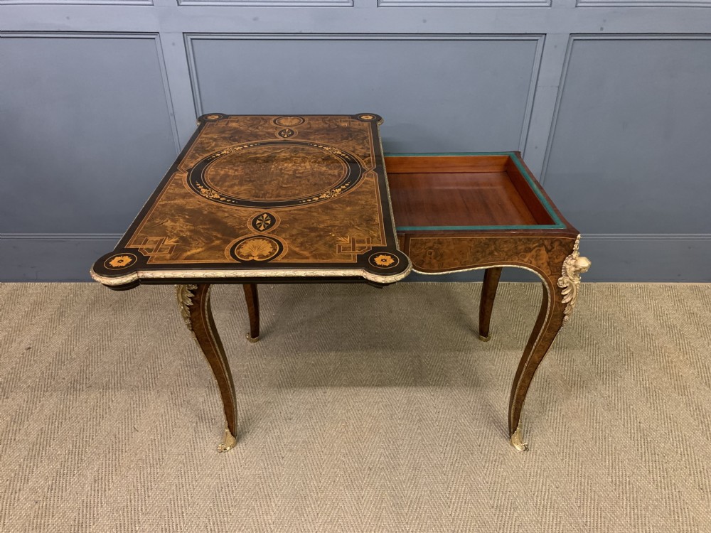 A 19th-century French burr walnut card table featuring intricate marquetry on the top, cabriole legs with gilt-bronze mounts, and a central porcelain plaque on the frieze. View XX