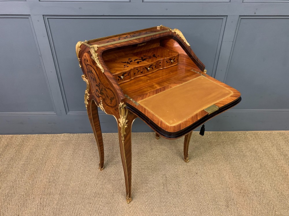 A French Louis XV style kingwood bureau de dame featuring floral marquetry inlays, gilt bronze ormolu mounts, slender cabriole legs, and a slant-front writing slope. View XVI