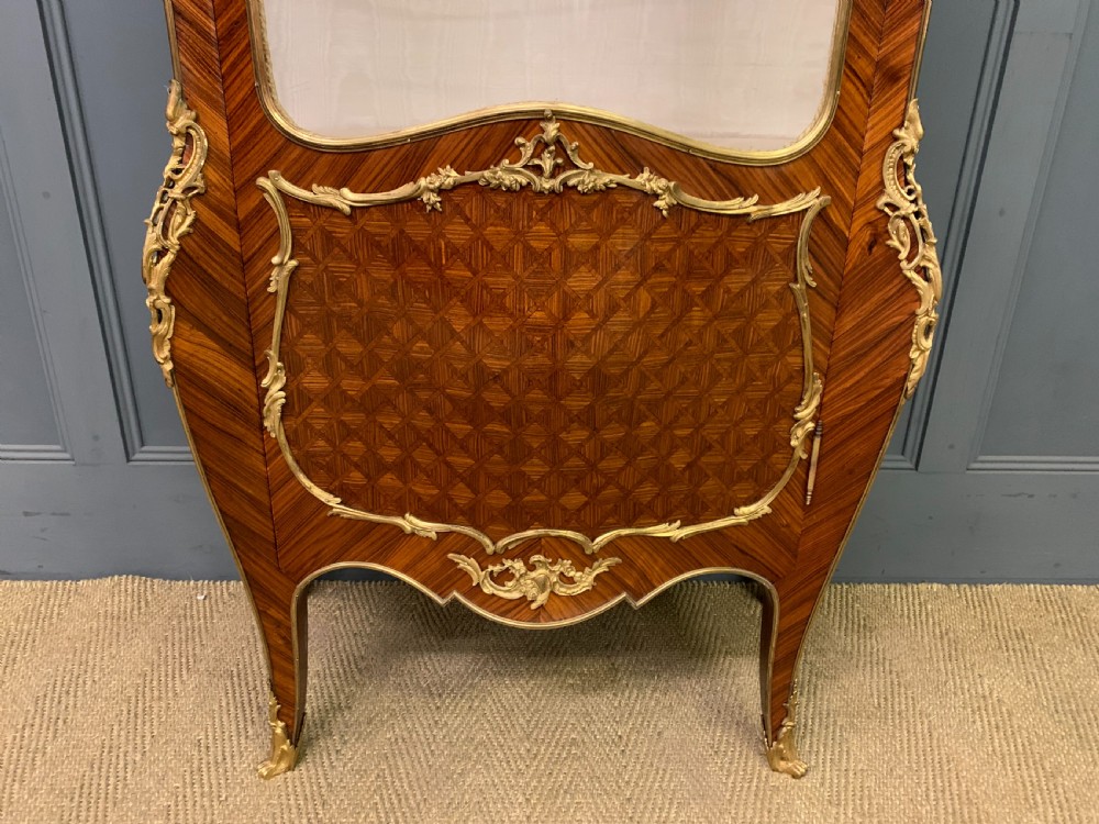 A 19th-century French kingwood vitrine cabinet with glass side panels, geometric parquetry lower door inlay, and ornate gilt-bronze ormolu mounts. View IV