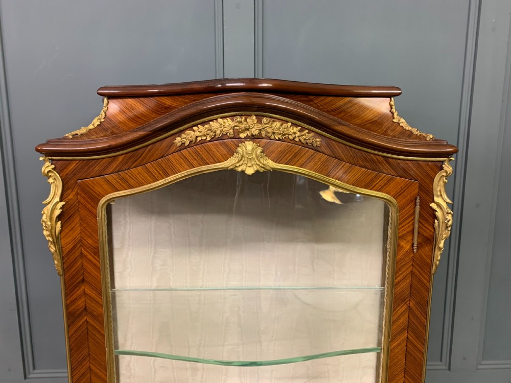 A 19th-century French kingwood vitrine cabinet with glass side panels, geometric parquetry lower door inlay, and ornate gilt-bronze ormolu mounts. View VIII