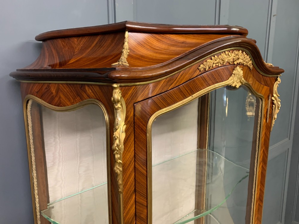 A 19th-century French kingwood vitrine cabinet with glass side panels, geometric parquetry lower door inlay, and ornate gilt-bronze ormolu mounts. View X
