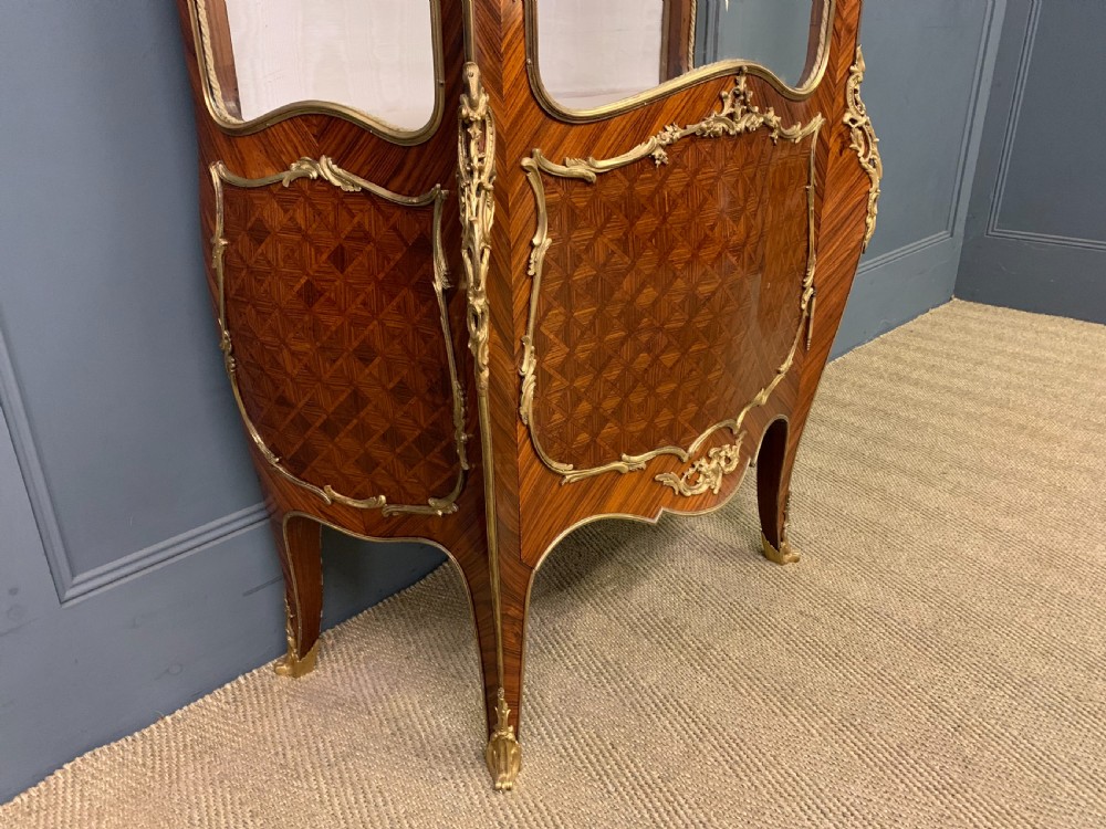 A 19th-century French kingwood vitrine cabinet with glass side panels, geometric parquetry lower door inlay, and ornate gilt-bronze ormolu mounts. View XI