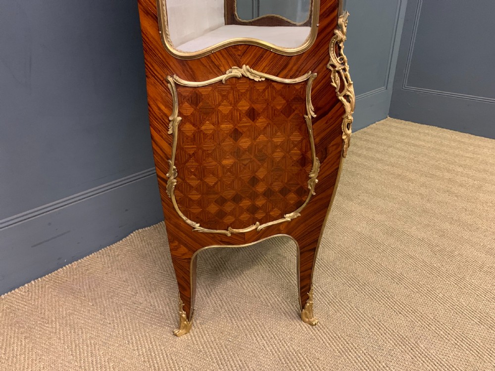 A 19th-century French kingwood vitrine cabinet with glass side panels, geometric parquetry lower door inlay, and ornate gilt-bronze ormolu mounts. View XIII