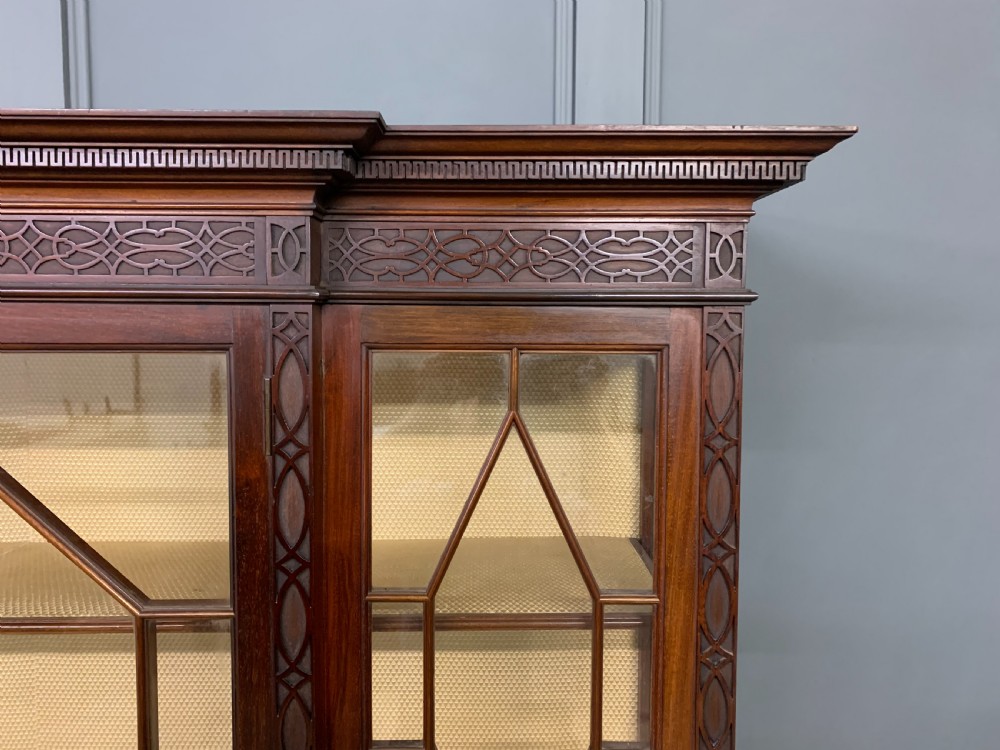A carved dark mahogany display cabinet featuring three astragal glazed doors above drawers and cabriole legs on an undertier shelf. View IV