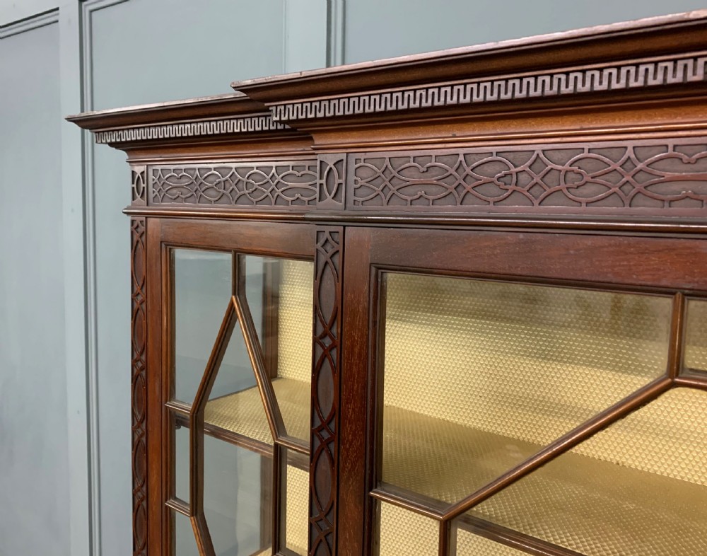 A carved dark mahogany display cabinet featuring three astragal glazed doors above drawers and cabriole legs on an undertier shelf. View V