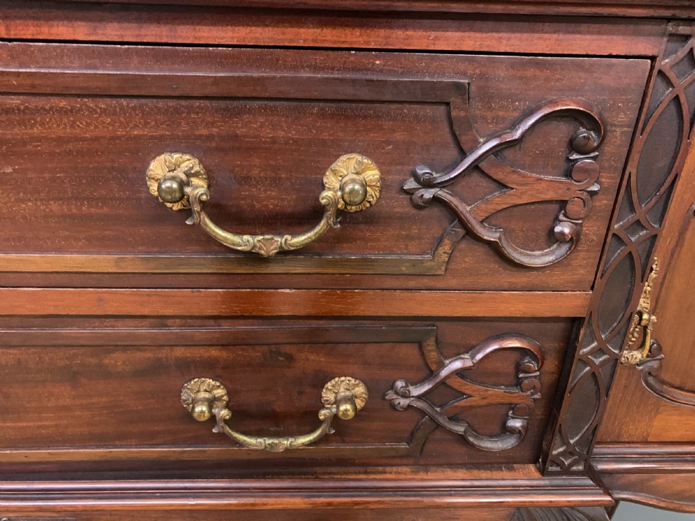 A carved dark mahogany display cabinet featuring three astragal glazed doors above drawers and cabriole legs on an undertier shelf. View VIII