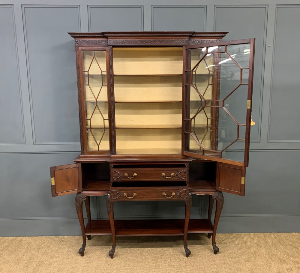 A carved dark mahogany display cabinet featuring three astragal glazed doors above drawers and cabriole legs on an undertier shelf. View XI