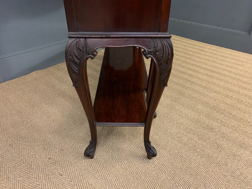 A carved dark mahogany display cabinet featuring three astragal glazed doors above drawers and cabriole legs on an undertier shelf. View XIV
