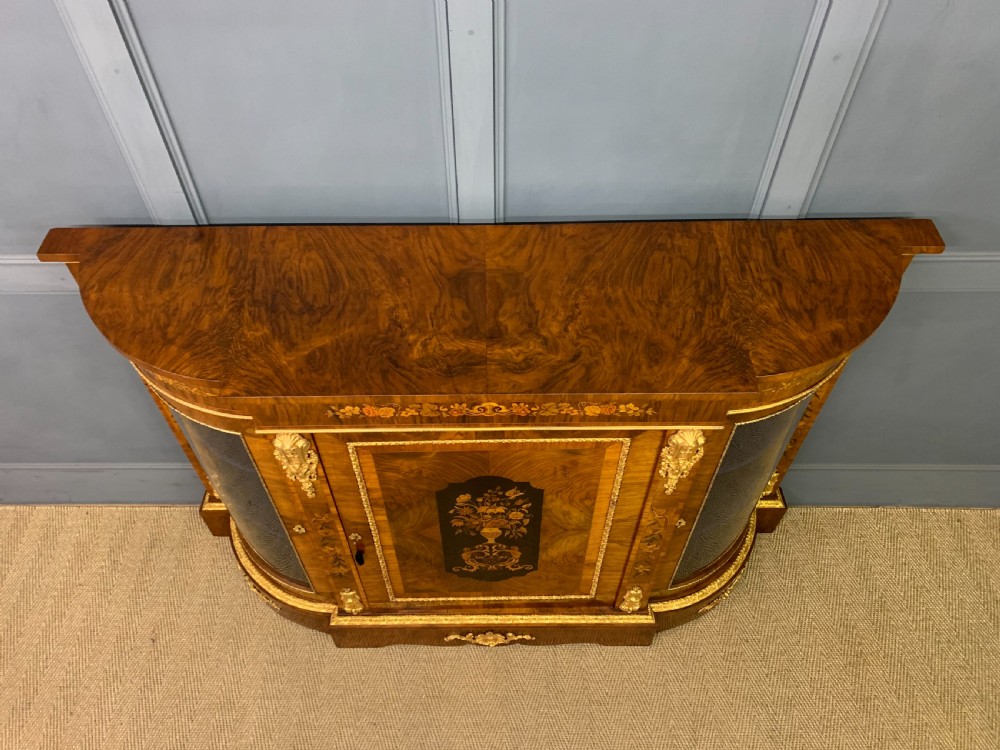 A Victorian burr walnut credenza featuring floral marquetry inlays, gilt bronze ormolu mounts, a central panelled door, and curved glazed side cabinets. View III