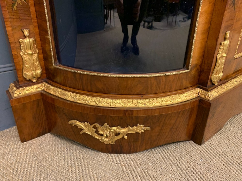 A Victorian burr walnut credenza featuring floral marquetry inlays, gilt bronze ormolu mounts, a central panelled door, and curved glazed side cabinets. View VIII
