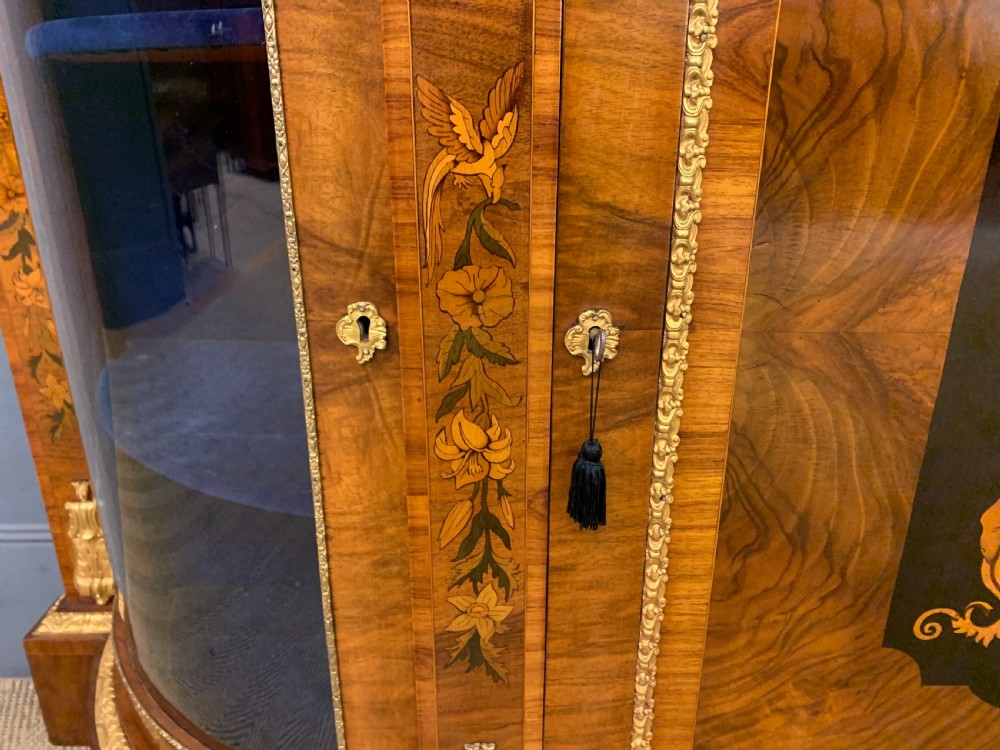 A Victorian burr walnut credenza featuring floral marquetry inlays, gilt bronze ormolu mounts, a central panelled door, and curved glazed side cabinets. View IX