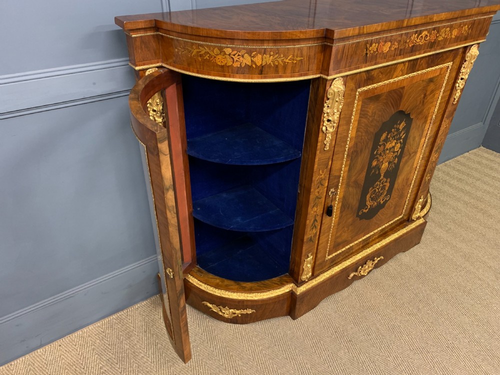 A Victorian burr walnut credenza featuring floral marquetry inlays, gilt bronze ormolu mounts, a central panelled door, and curved glazed side cabinets. View XIV