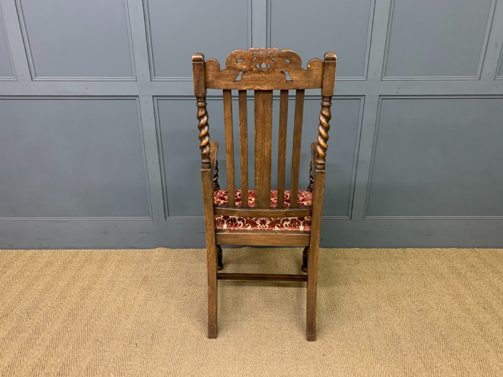 A dark oak armchair with barley twist uprights, a carved cresting rail, a vertical slat back, and a red patterned velvet upholstered seat pad. View VIII