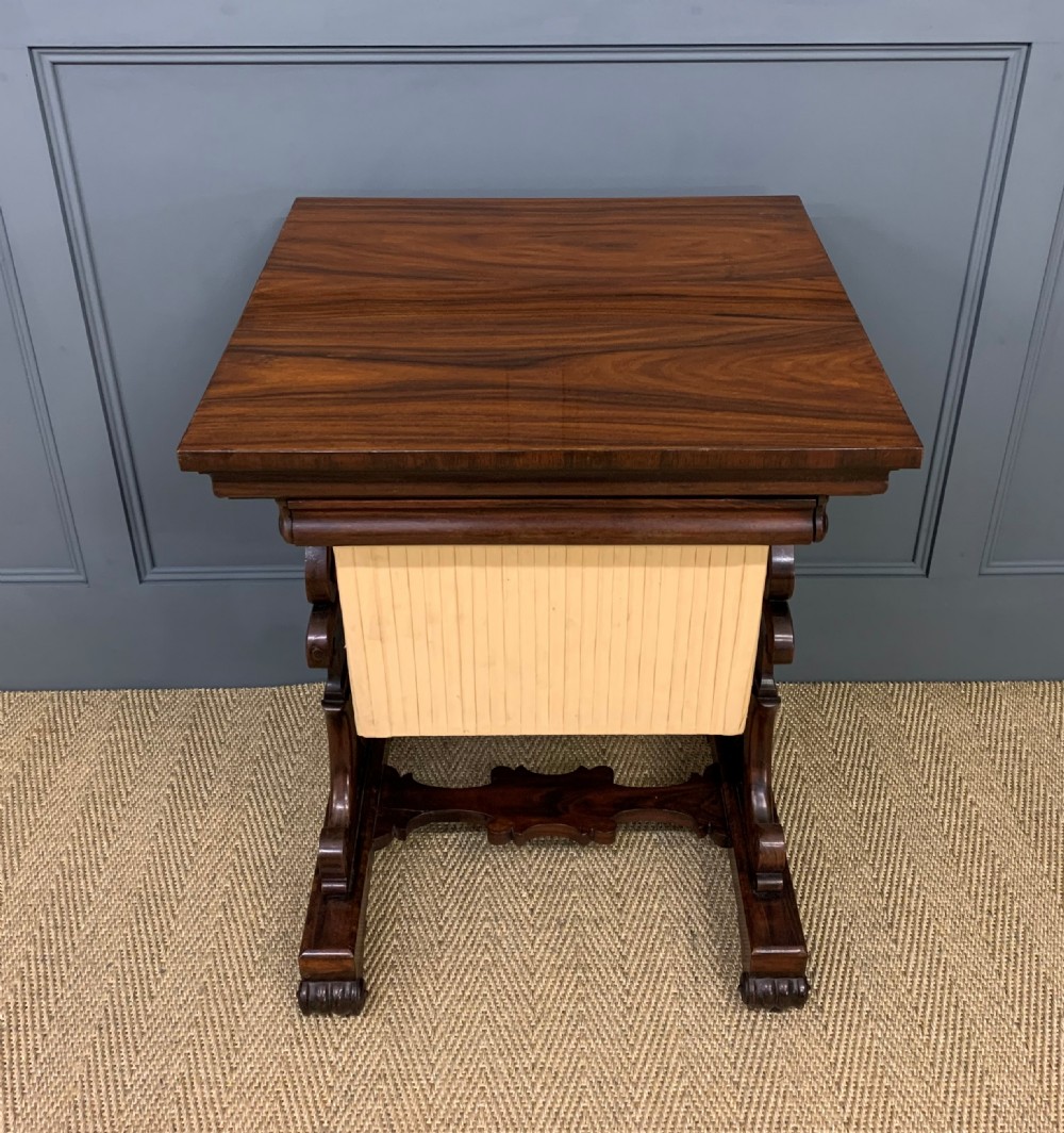 A William IV rosewood work table featuring a figured square top, pleated cream fabric basket, and carved scroll supports. View II